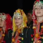 Amazigh women in traditional headdresses and silver jewellery at a night performance